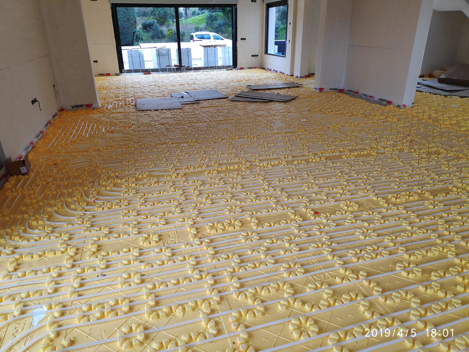 Proceso de colocación de tuberías para suelo radiante sobre placa de aislamiento.